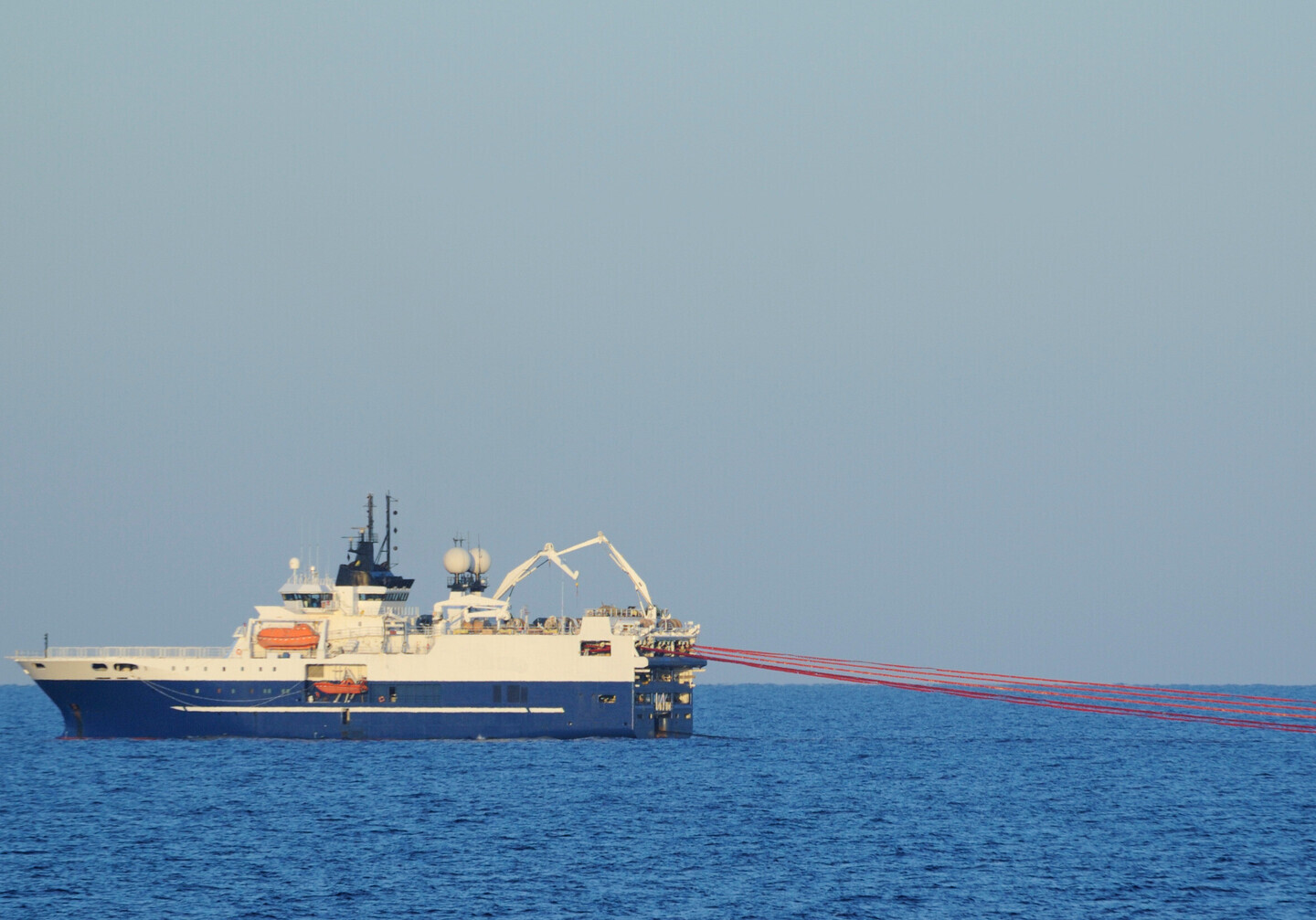 Seismic acquisition cables towed by a ship at sea.